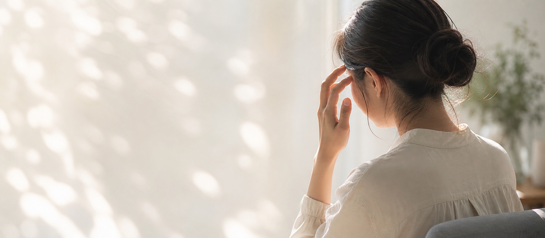 明るい室内で頭痛に悩む女性のイメージ